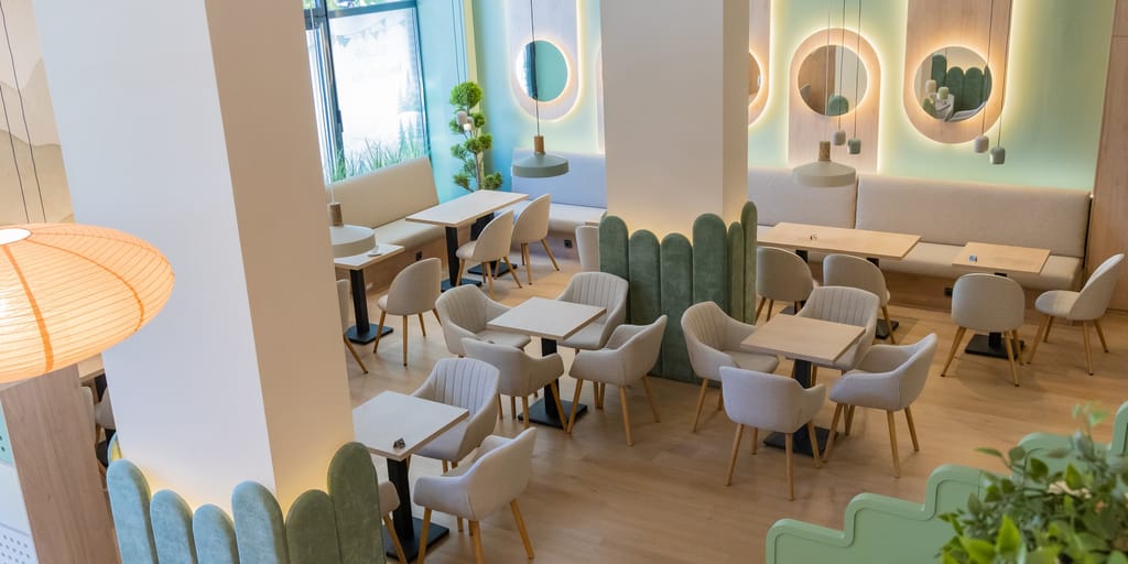 Kafe-bar za roditelje sa toplim osvetljenjem i zelenim paravanima
